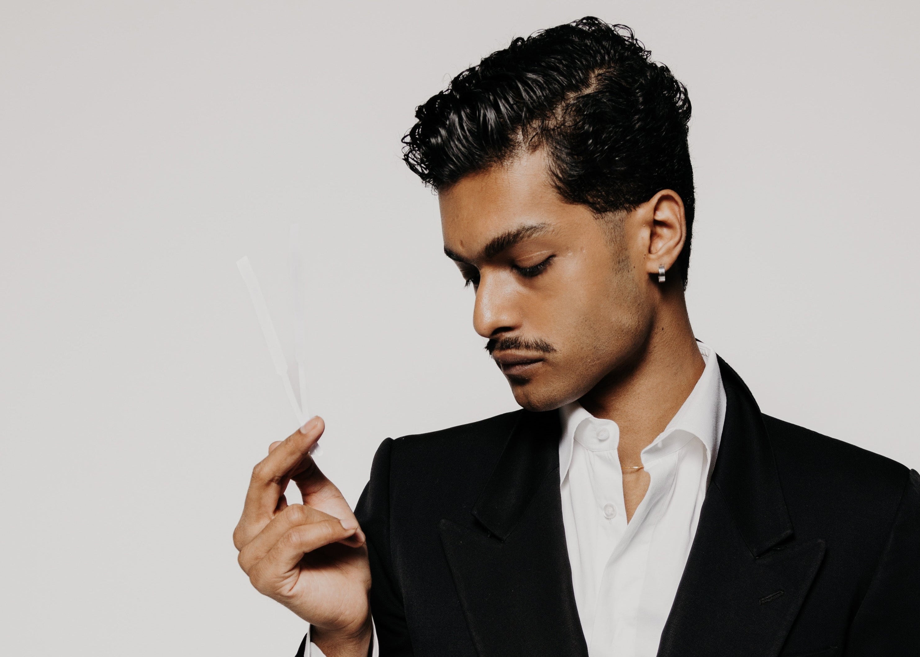 Man wearing a black suit with a white shirt on a plain background